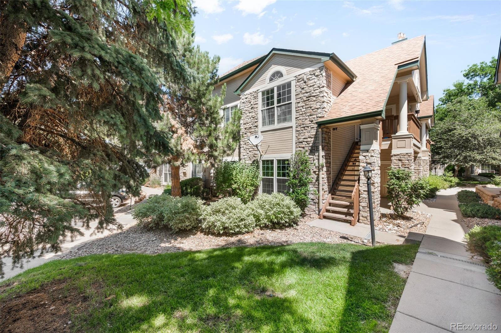 4064 South Carson Street, Unit 101 Aurora, CO 80014 - Photo 1 of 19 a view of a house with brick walls and a yard with plants and a large tree