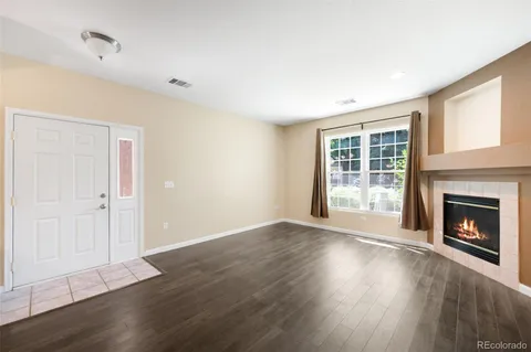 a view of an empty room with wooden floor fireplace and a window