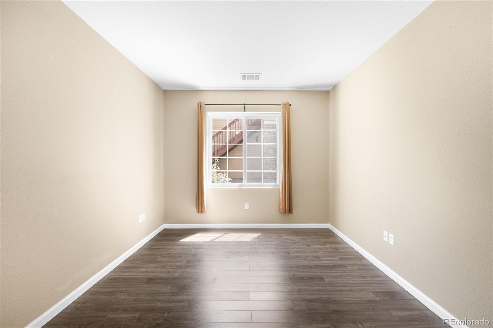 4064 South Carson Street, Unit 101 Aurora, CO 80014 - Photo 9 of 19 a view of an empty room with wooden floor and a window