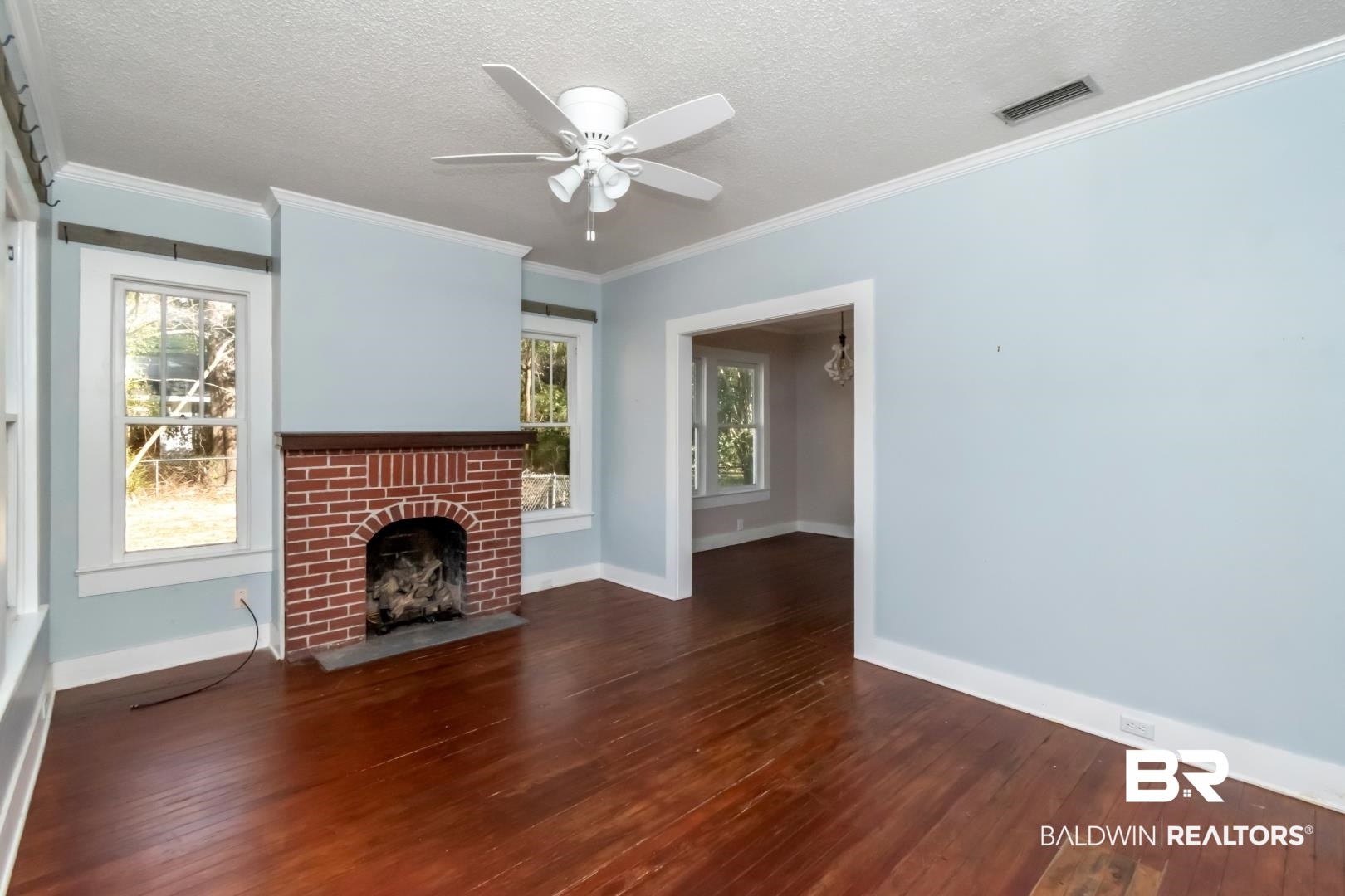 731 Jemison Street Mobile, AL 36606 - Photo 4 of 27 Unfurnished living room featuring a textured ceiling, crown molding, a ceiling fan, dark wood-style floors, and a brick fireplace