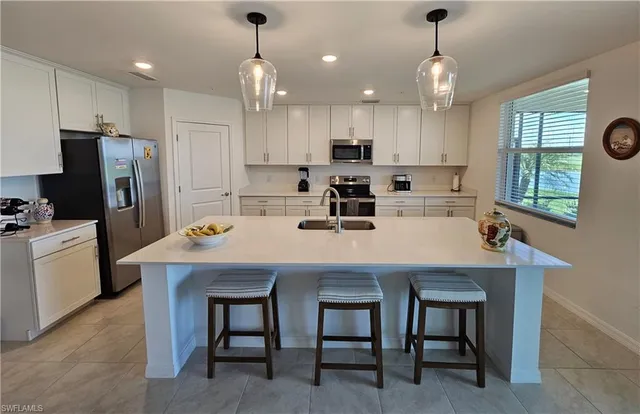 a kitchen with kitchen island cabinets a sink stainless steel appliances and window