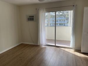 105 Mansfield F, Unit C Boca Raton, FL 33434 - Photo 8 of 14 an empty room with wooden floor and windows