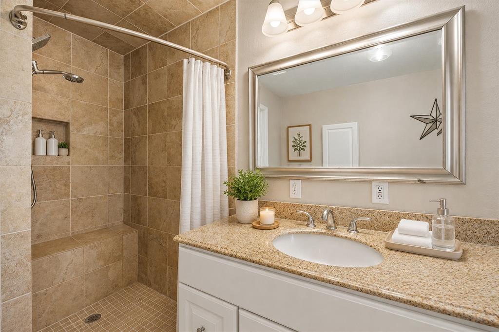 1547 Magnolia Lane Wills Point, TX 75169 - Photo 9 of 22 Shower with integrated bench and niche, white vanity with an undermount sink, granite countertop, and a large framed mirror