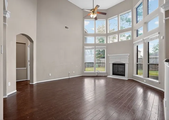 an empty room with wooden floor fireplace and windows