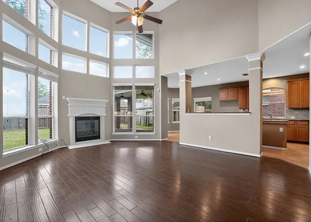 a view of an empty room with wooden floor and a kitchen