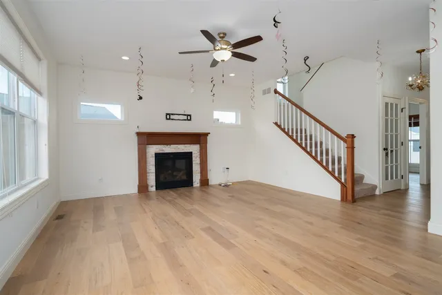 a view of an empty room with chandelier fan and wooden floor