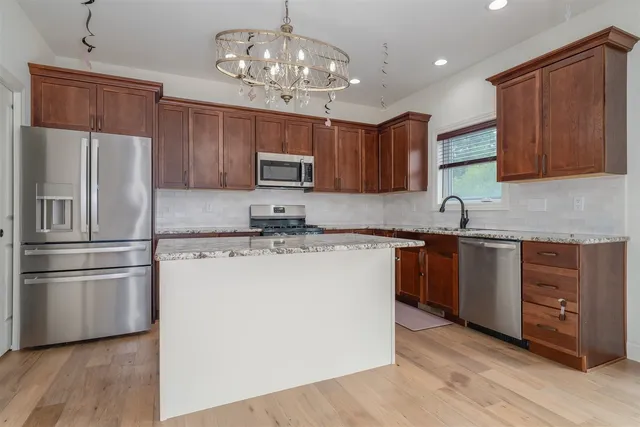a kitchen with kitchen island granite countertop wooden cabinets a refrigerator and a sink