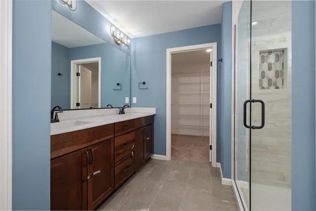 a bathroom with a double vanity sink a mirror and a shower