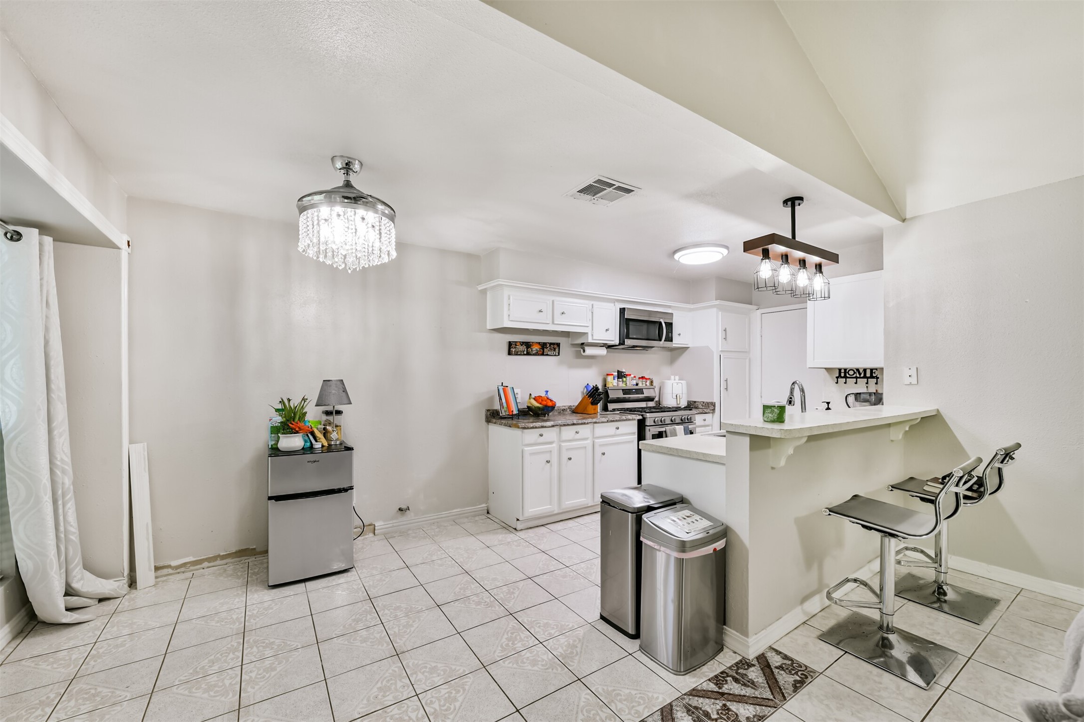 15105 Silverman Street Houston, TX 77598 - Photo 12 of 26 The dining area featuring an elegant chandelier, complemented by a cozy breakfast bar perfect for casual dining.