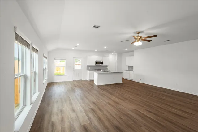 a view of an empty room with wooden floor and a window
