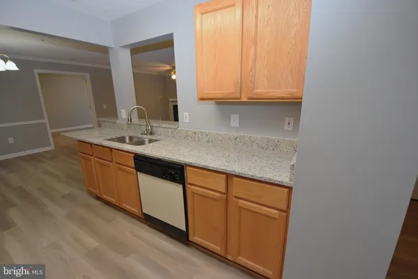 a kitchen with stainless steel appliances granite countertop a sink and cabinets with wooden floor