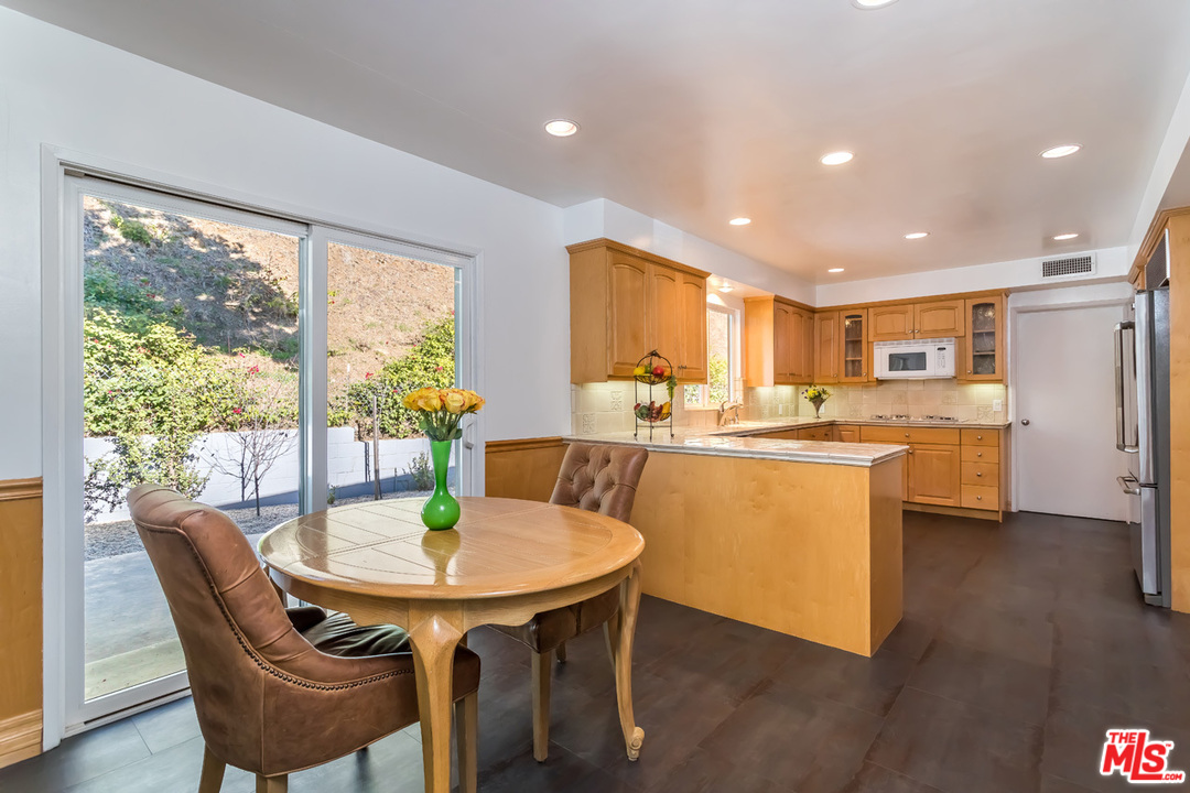 9767 Beth Place Beverly Hills, CA 90210 - Photo 16 of 33 a dining room with stainless steel appliances a dining table wooden floor and a kitchen view