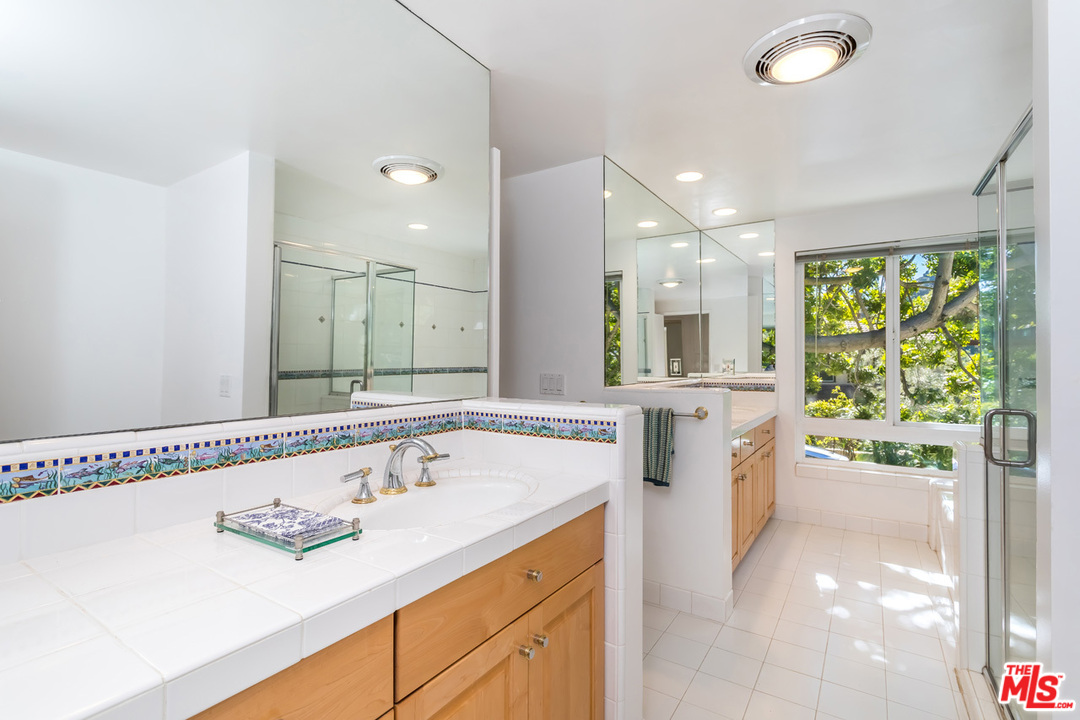 9767 Beth Place Beverly Hills, CA 90210 - Photo 23 of 33 a bathroom with a sink a large mirror and a bathtub