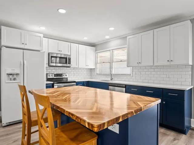 a kitchen with stainless steel appliances granite countertop a table chairs sink refrigerator and microwave