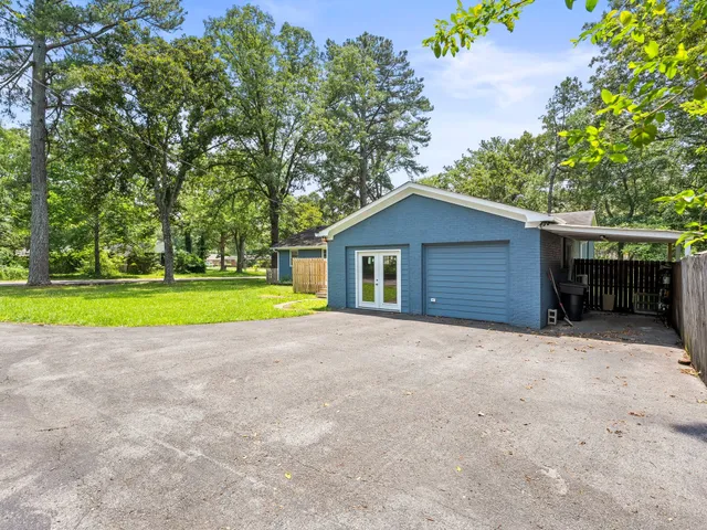 a view of yellow house with a big yard and large trees