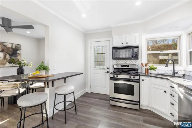 a kitchen with granite countertop a stove a sink and a microwave