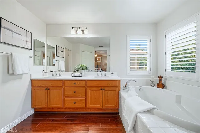 a spacious bathroom with double vanity a mirror a bathtub and a window