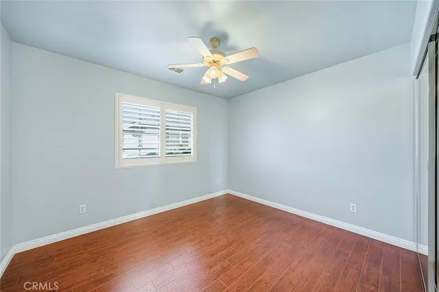 an empty room with wooden floor a ceiling fan and windows