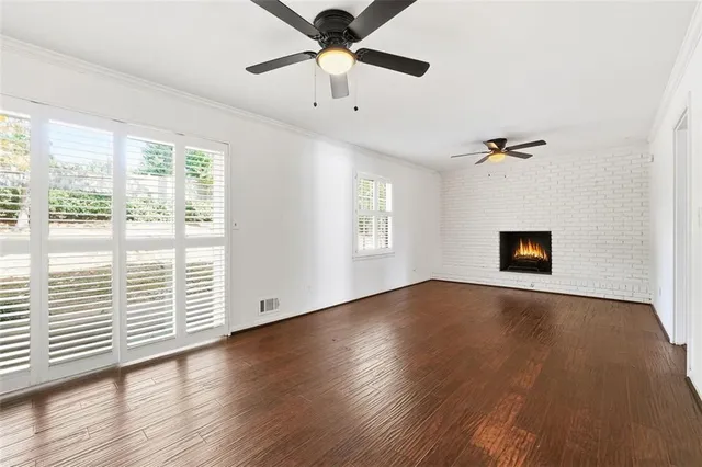 an empty room with wooden floor fan and windows