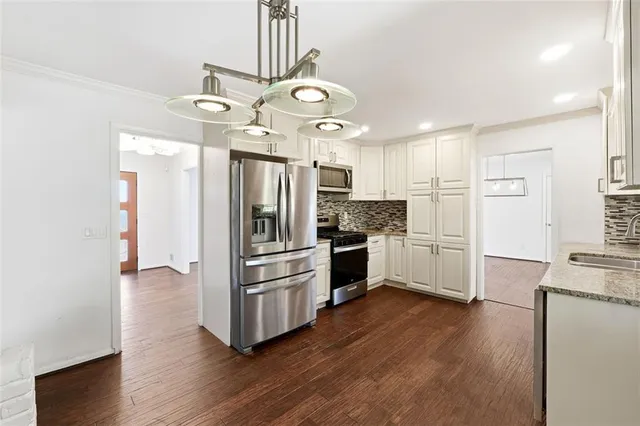 a kitchen with stainless steel appliances a refrigerator and wooden floor
