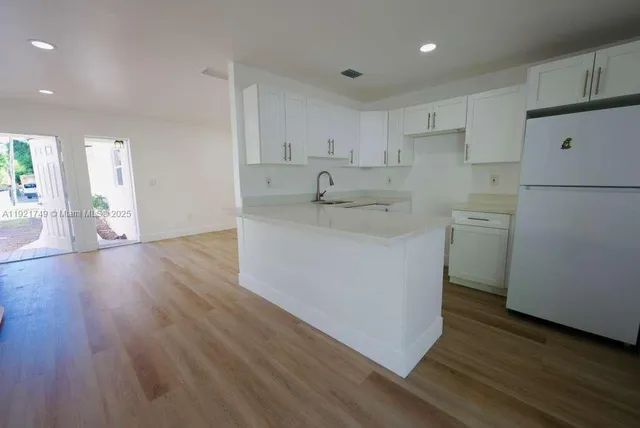 a kitchen with a sink a refrigerator and white cabinets