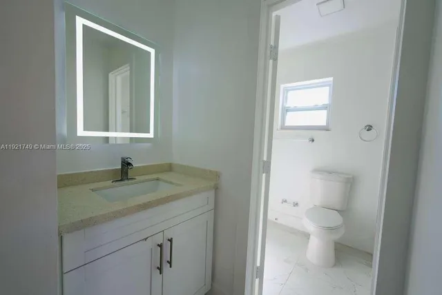 a bathroom with a granite countertop sink a toilet and a mirror