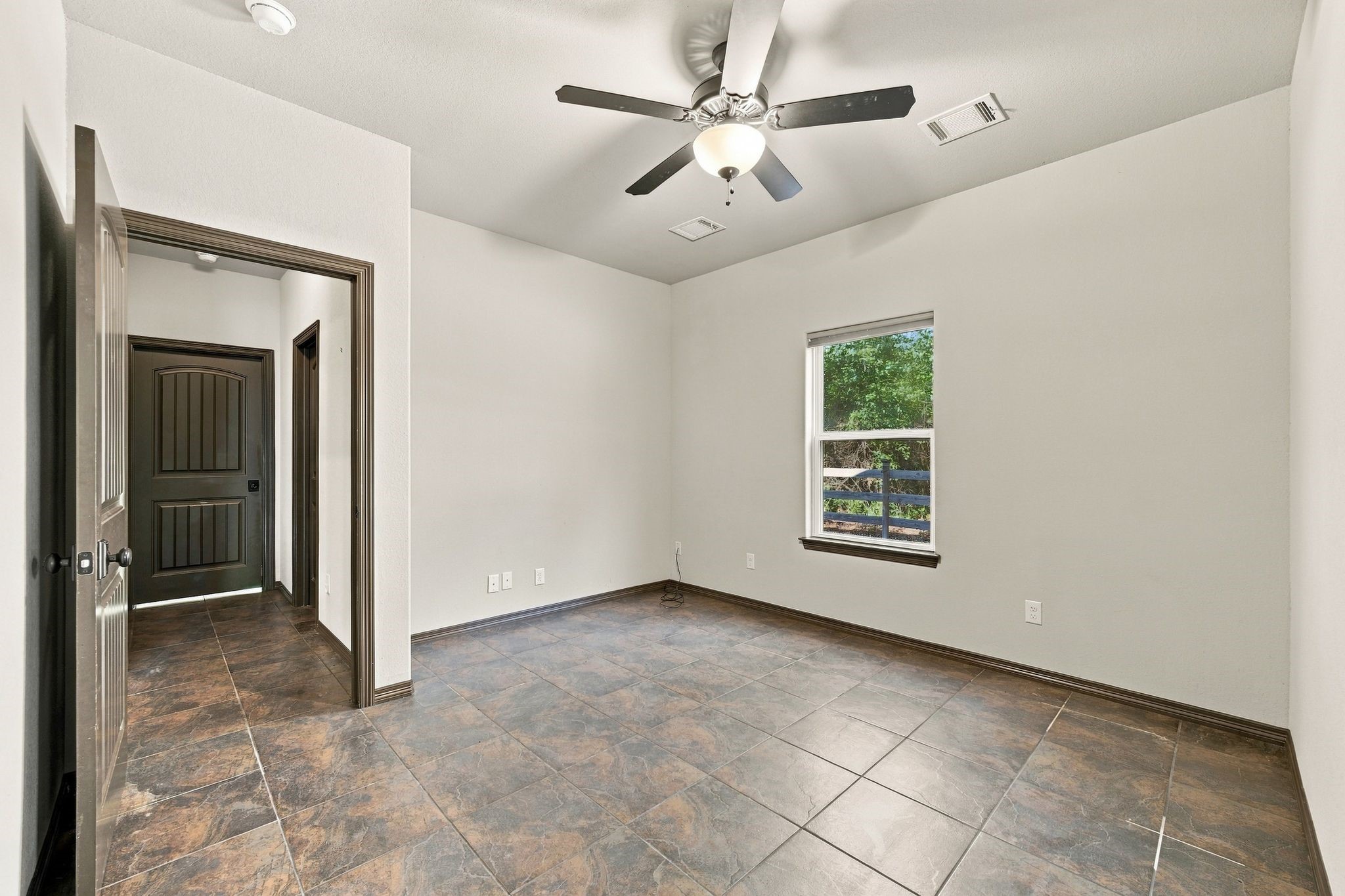 7049 Pine Shadows Road Cleveland, TX 77328 - Photo 25 of 49 Bright room with large tile flooring, neutral walls, and a ceiling fan, featuring a window that allows natural light and a view of greenery.