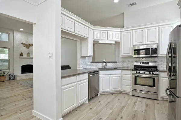 a kitchen with cabinets stainless steel appliances and wooden floor