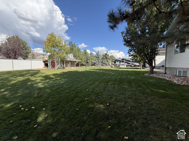 1750 West 4100 North Helper, UT 84526 - Photo 45 of 50 Expansive grassy backyard featuring a detached shed with a covered porch, mature trees, and a privacy fence
