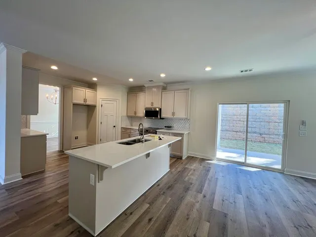 a large kitchen with a large counter top a sink stainless steel appliances and cabinets