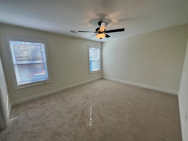 an empty room with windows and fan