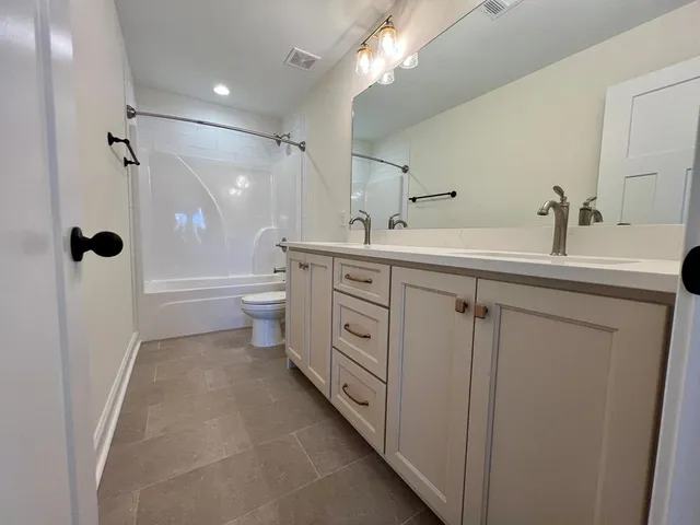 a bathroom with a double vanity sink toilet mirror and shower