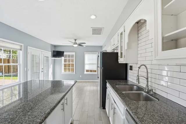 a kitchen with granite countertop a sink a counter top space and stainless steel appliances