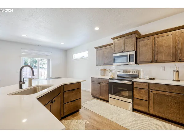 a kitchen with stainless steel appliances granite countertop a stove a sink dishwasher and a microwave oven with white cabinets