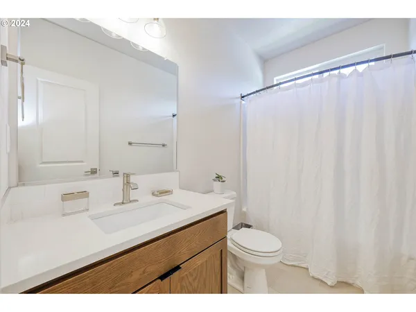 a bathroom with a sink a toilet a mirror and shower curtain