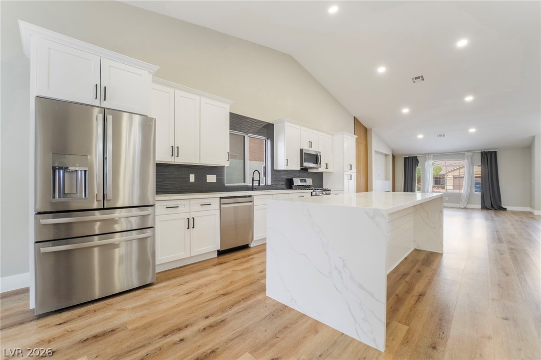 9171 West Viking Road Las Vegas, NV 89147 - Photo 16 of 43 Culinary dreams come alive in this kitchen, featuring an oversized island and vaulted ceilings that open to an adjacent living area.