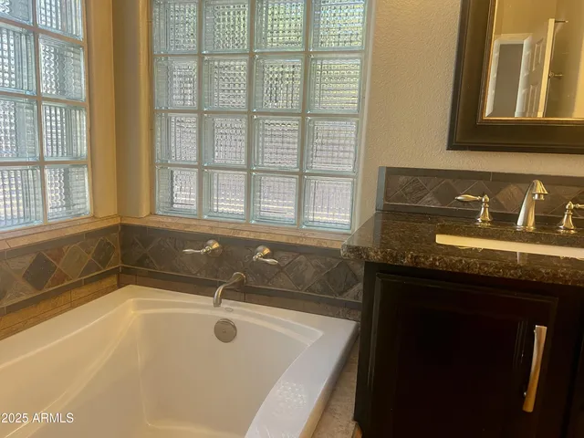 a bathroom with a granite countertop sink and a bathtub