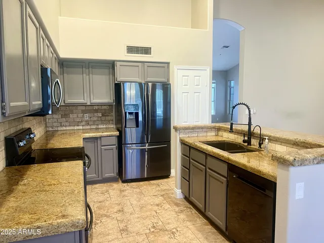 a kitchen with stainless steel appliances granite countertop a sink stove and refrigerator