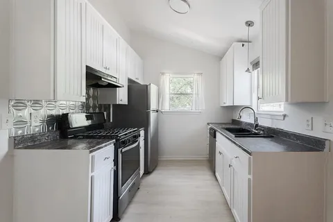 a kitchen with stainless steel appliances granite countertop a sink stove a refrigerator a sink and dishwasher with wooden floor