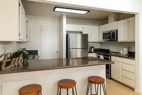 a kitchen with stainless steel appliances granite countertop a refrigerator a sink a stove and white cabinets