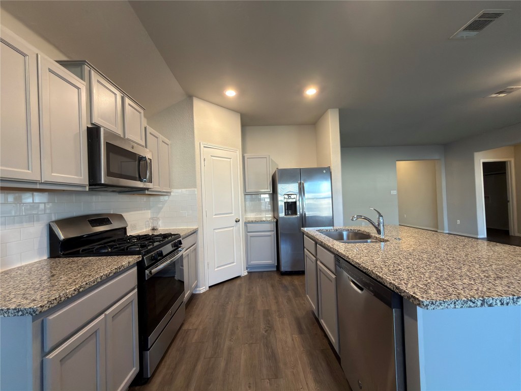 a kitchen with stainless steel appliances granite countertop a sink stove microwave and refrigerator