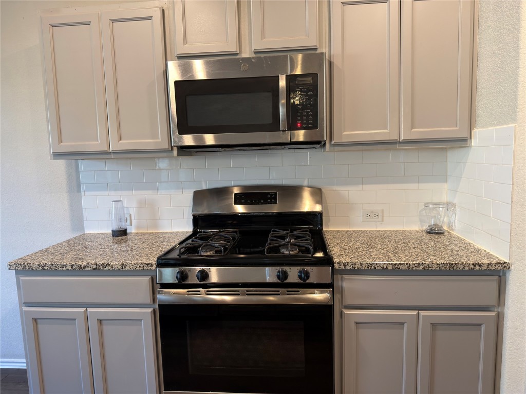 21700 Urraca Lane Pflugerville, TX 78660 - Photo 6 of 40 a kitchen with granite countertop white cabinets and a stove top oven