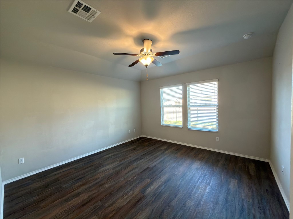 21700 Urraca Lane Pflugerville, TX 78660 - Photo 9 of 40 an empty room with wooden floor ceiling fan and windows