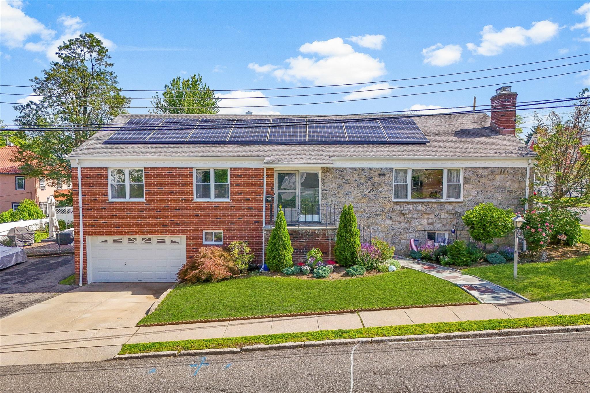 View of front of home featuring a front lawn, concrete driveway, a garage, solar panels, and roof with shingles