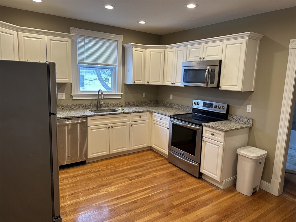 225 Gibson Street, Unit 2 Lowell, MA 01851 - Photo 1 of 13 a white kitchen with wooden cabinets and white appliances