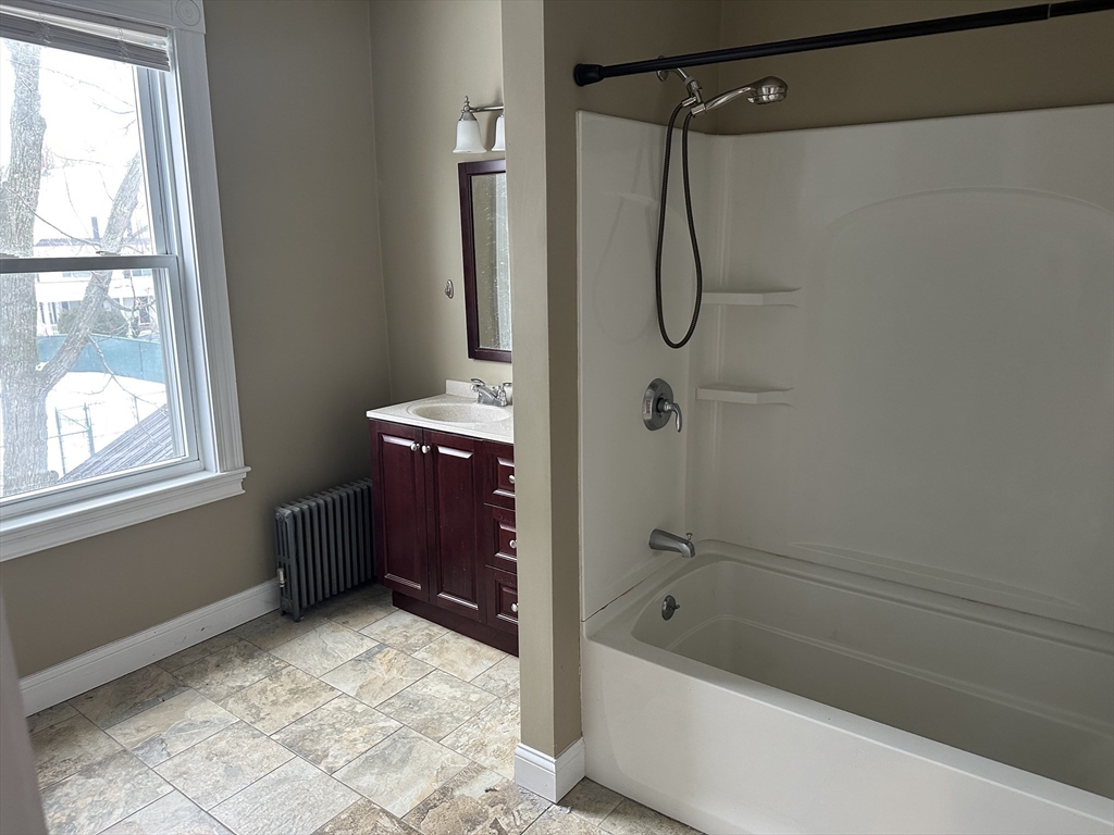225 Gibson Street, Unit 2 Lowell, MA 01851 - Photo 12 of 13 a bathroom with a bath tub a shower and a window