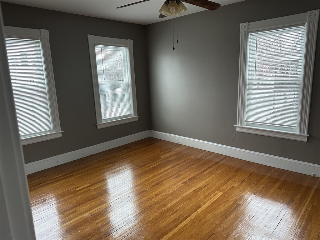 225 Gibson Street, Unit 2 Lowell, MA 01851 - Photo 5 of 13 a view of an empty room with wooden floor and a window