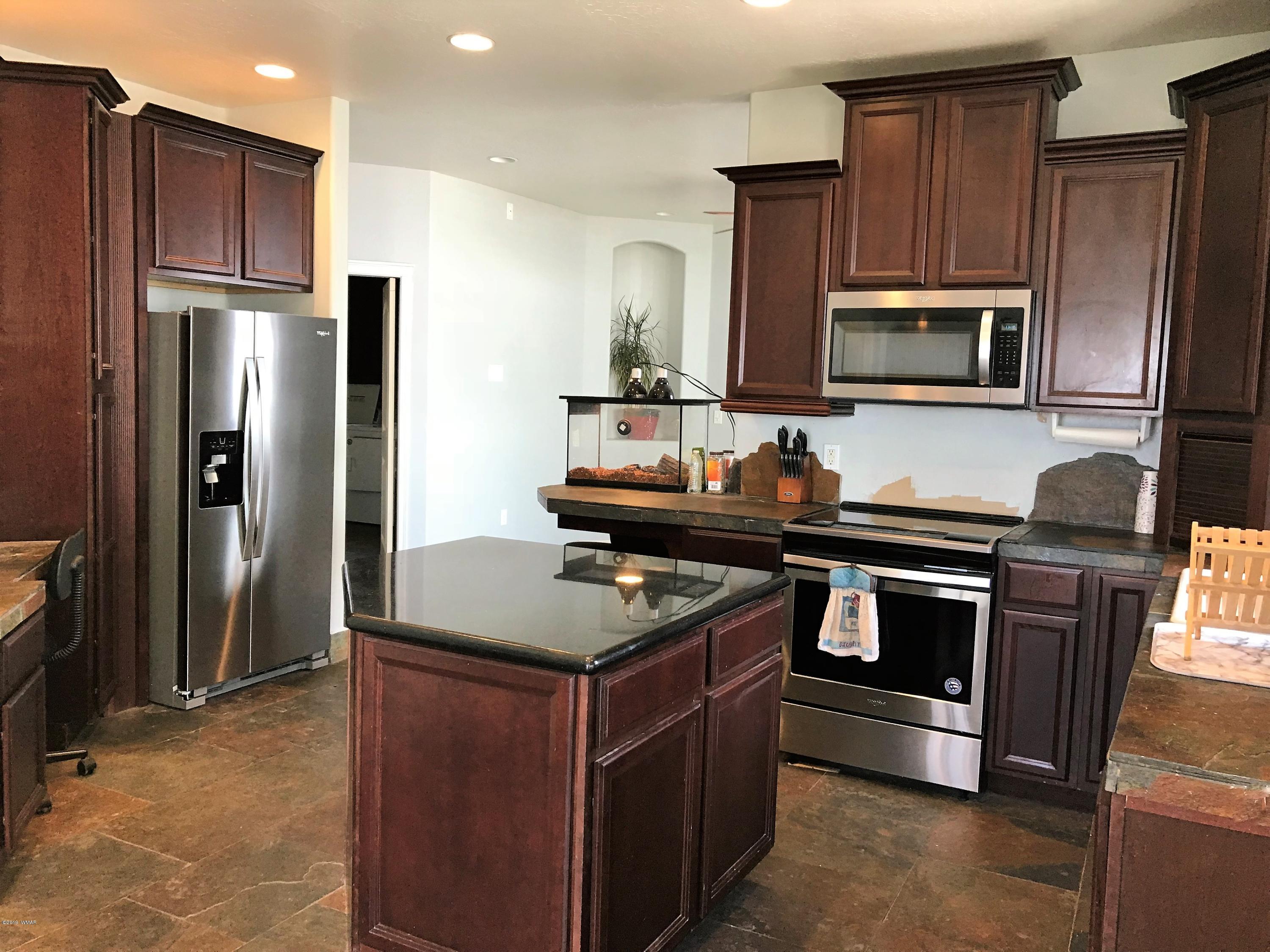 526 South 6th W Street Snowflake, AZ 85937 - Photo 14 of 36 a kitchen with kitchen island granite countertop stainless steel appliances and wooden cabinets