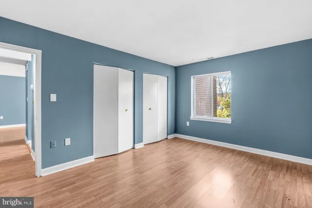 a view of an empty room with window and wooden floor