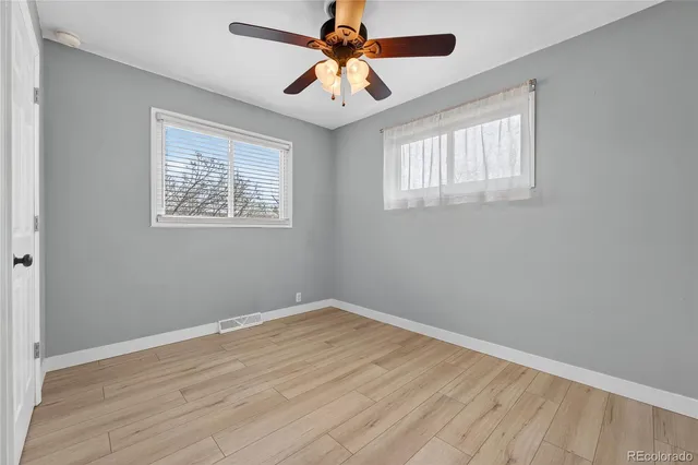 a view of an empty room with window and a chandelier fan